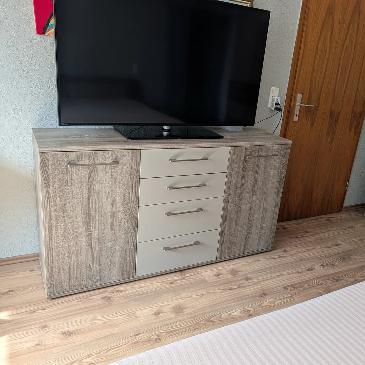 Sideboard mit vier Schubladen und zwei Türen, darauf ein Fernseher